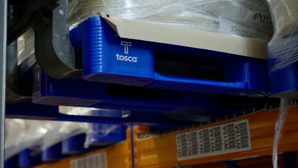 Close-up of a Tosca-branded blue reusable plastic pallet, highlighting its sturdy construction and stackable design for efficient warehouse storage and transport.