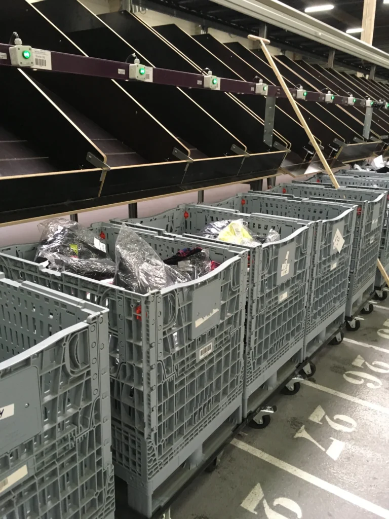 Gray textile bins in a distribution center filled with product. Tosca display bins help optimise the warehouse picking process and can easily move through the textile supply chain, from transport and storage to display.