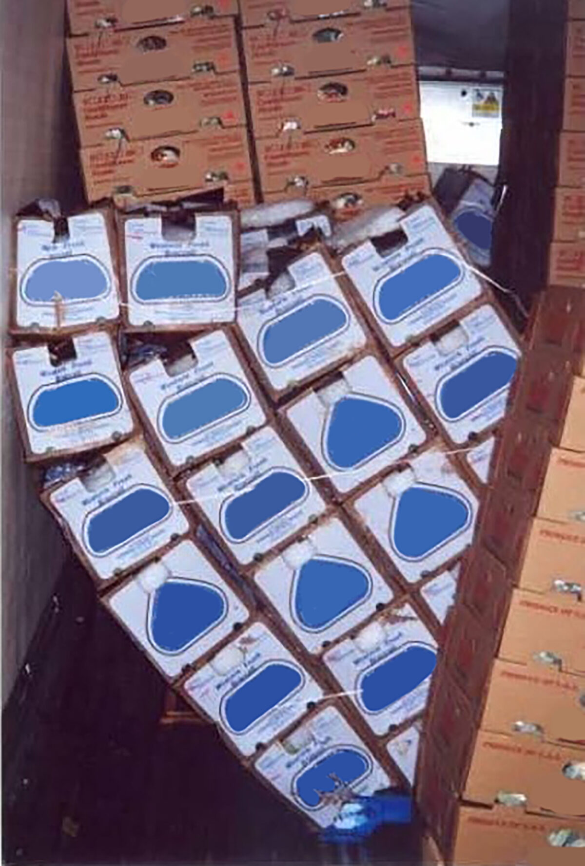 Stacked corrugated cardboard boxes have fallen over and been crushed in the back cargo space of a freight delivery truck.