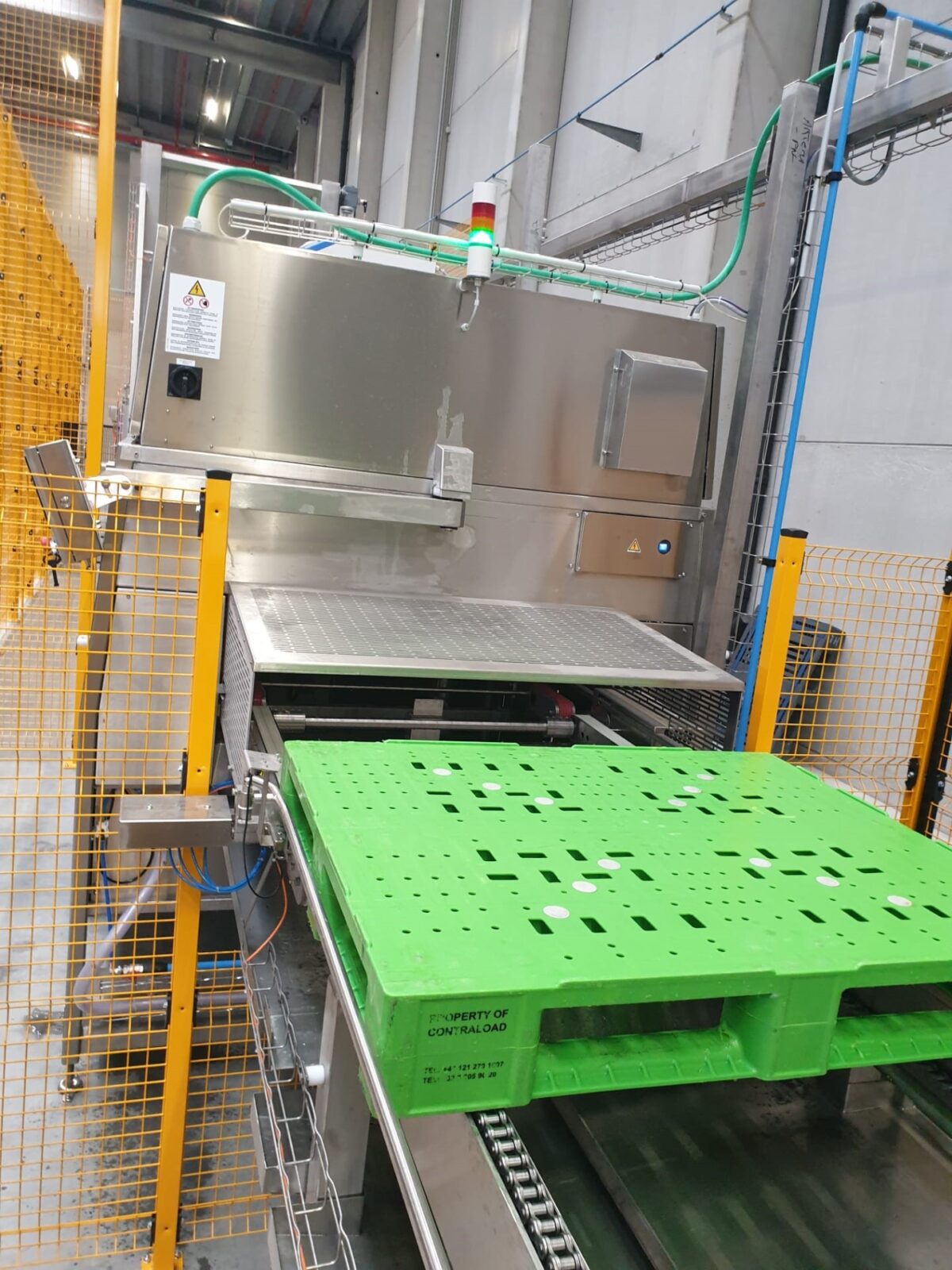 Tosca reusable green pallet moving down a conveyor at a service centre as part of Tosca’s reusable asset sanitation process to ensure food safety.