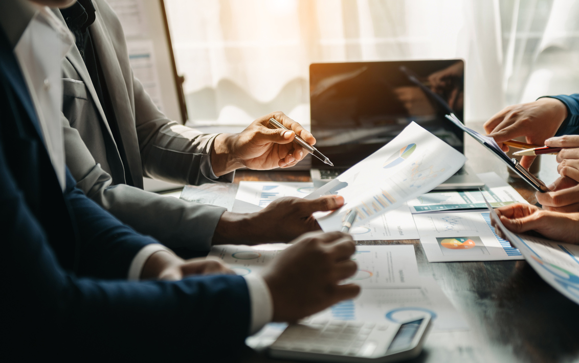 Business documents on office table with smart phone and calculator digital tablet and graph business with social network diagram and two colleagues discussing data working