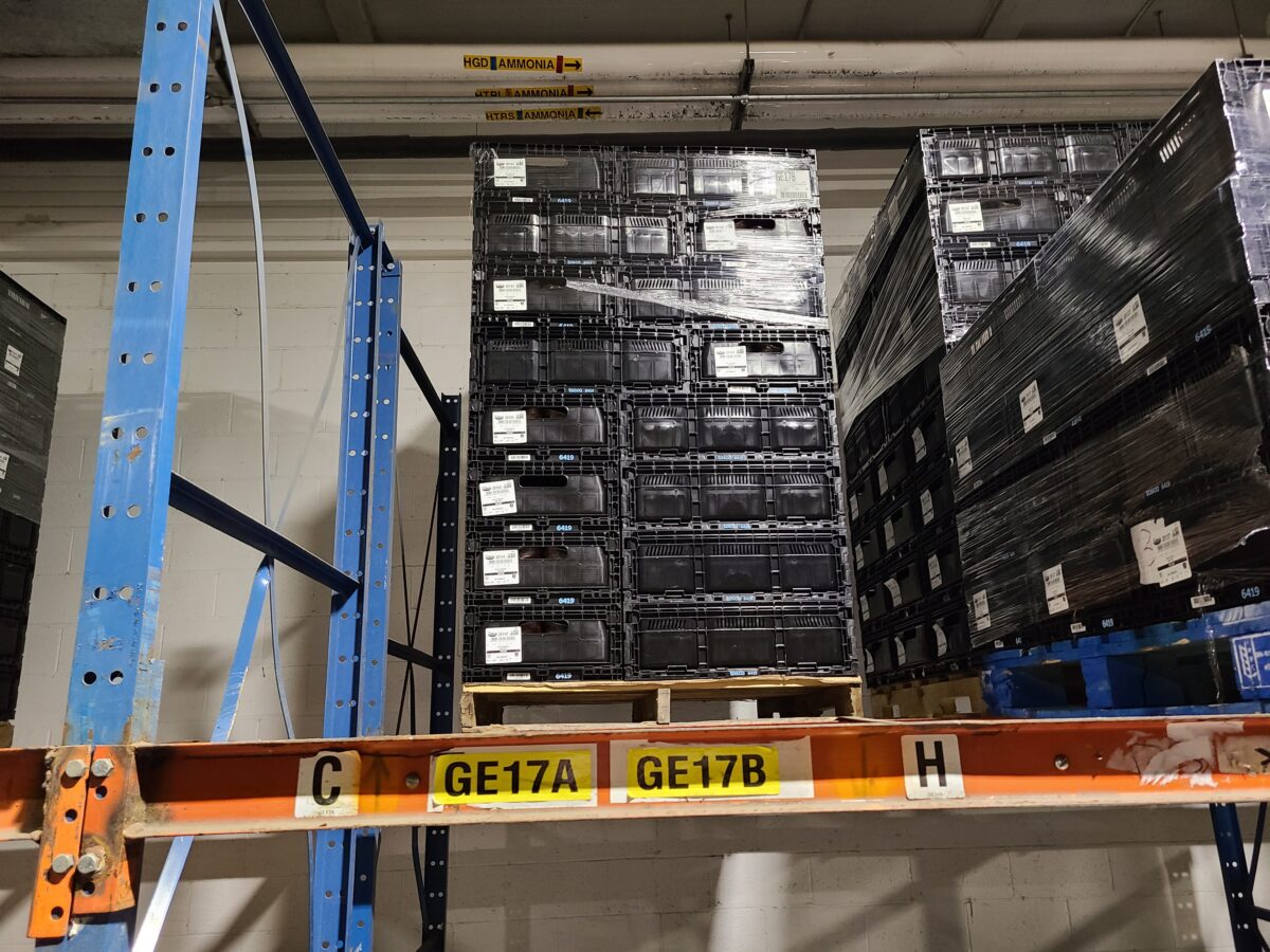 A neatly stacked pallet of reusable plastic pallets sitting safely on a rack inside of a distribution center.
