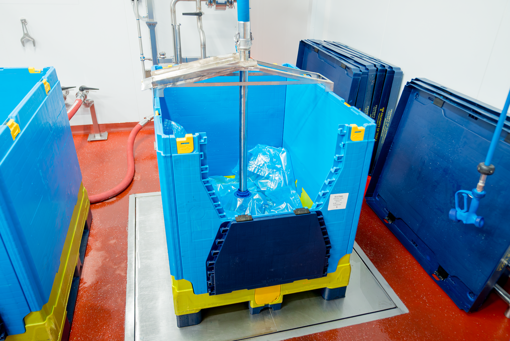 Blue reusable plastic bulk container equipped with a liquid liner, ready to be filled, providing a secure and hygienic solution for transporting large quantities of liquid products such as fruit purees.