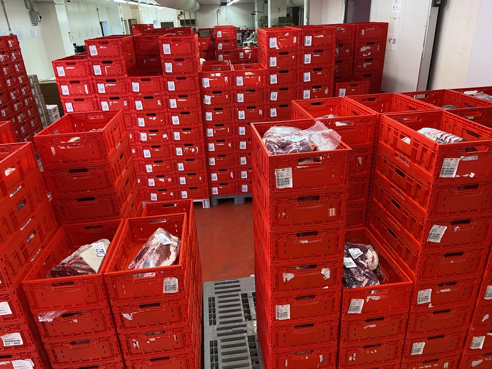 Tosca reusable plastic meat shipping containers filled with packaged meat products, demonstrating its use in a supply chain setting for safe and efficient transport