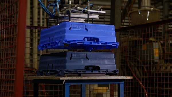 A blue custom Tosca crate being formed from a product mold by an automated machine in a production facility.