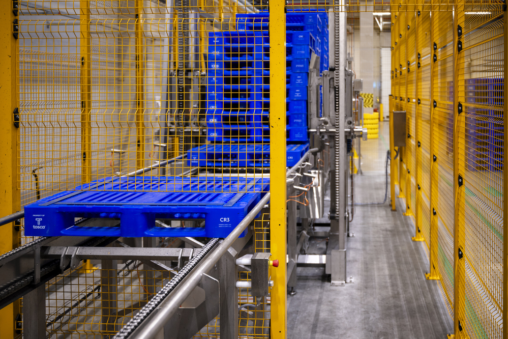 A freshly cleaned blue reusable pallet exiting an automated washer. Tosca ensures high food safety and quality assurance for optimal sanitation.