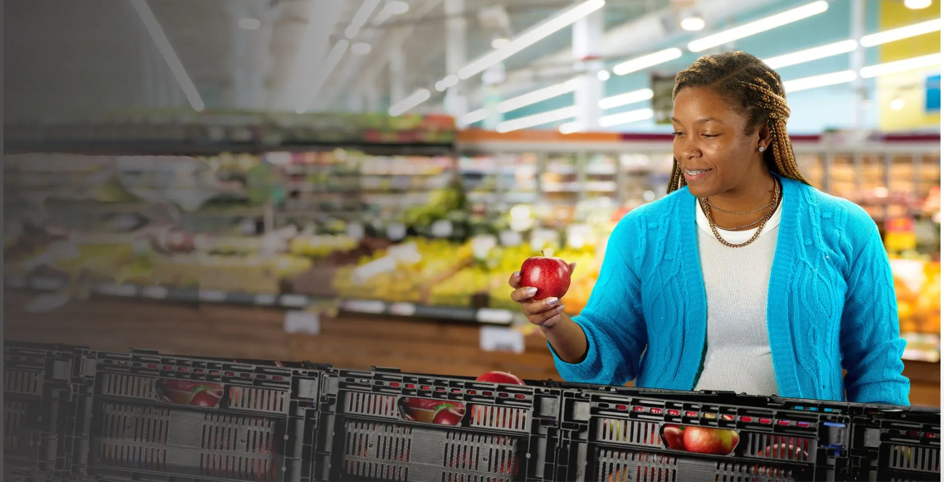 Woman in grocery store shops for fresh produce out of a reusable plastic container or RPC