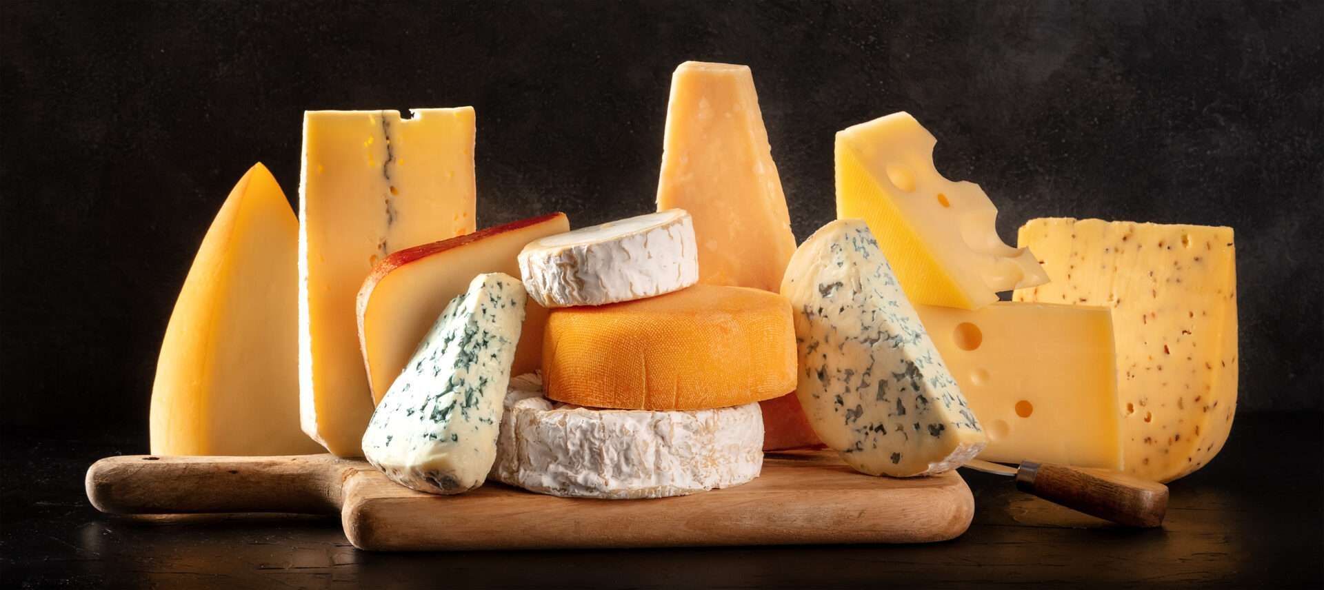 Cheese panorama with French, Italian, and Spanish cheeses on a dark background