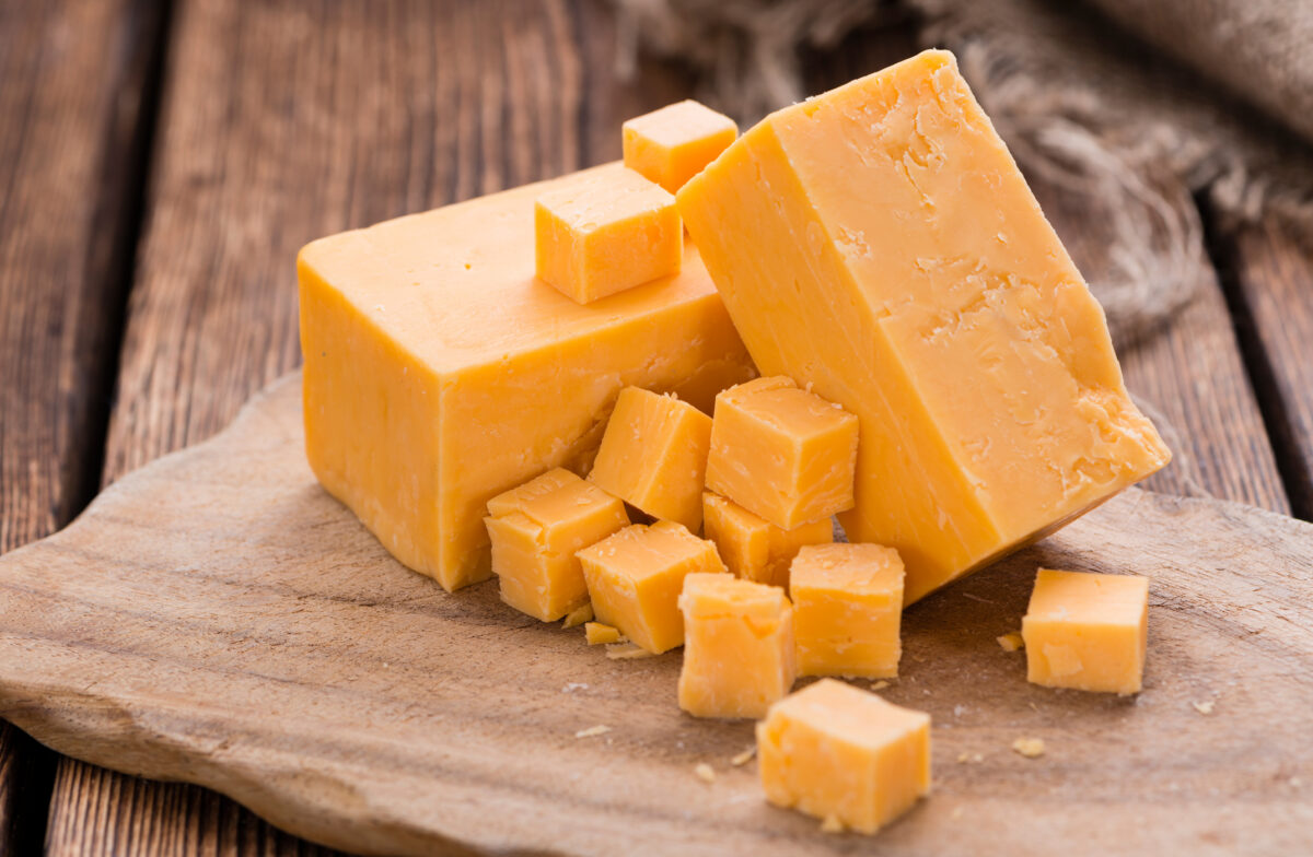 Cubed cheddar on a wooden cutting board