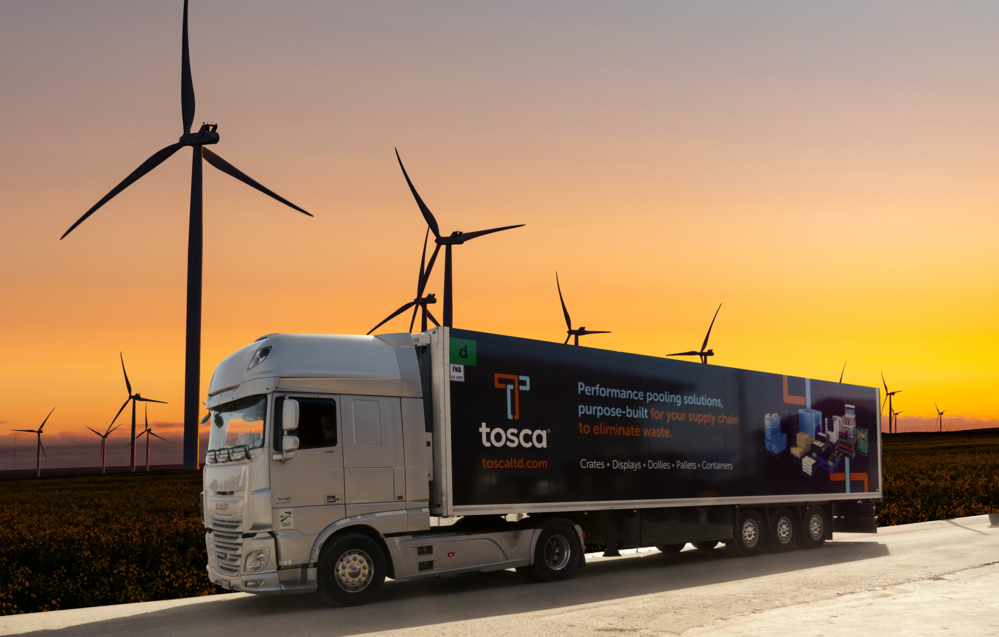 Tosca truck drives on the highway at dawn, passing by a windmill farm to deliver products to customers.