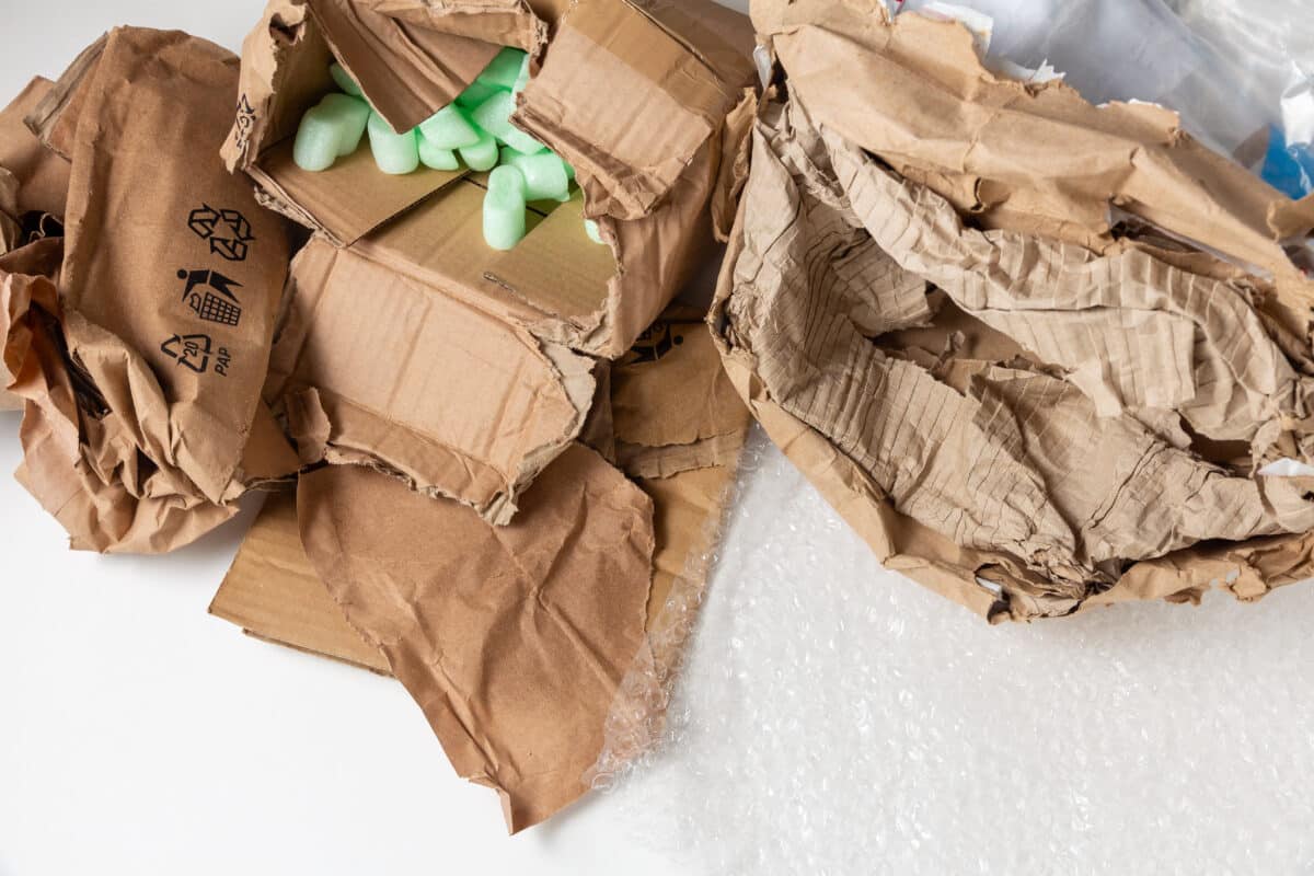 Wet damaged crumpled cardboard package with polyethylene and soft filling.
