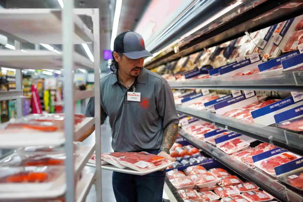 A worker in Brookshire brothers putting fresh meat on the shelf