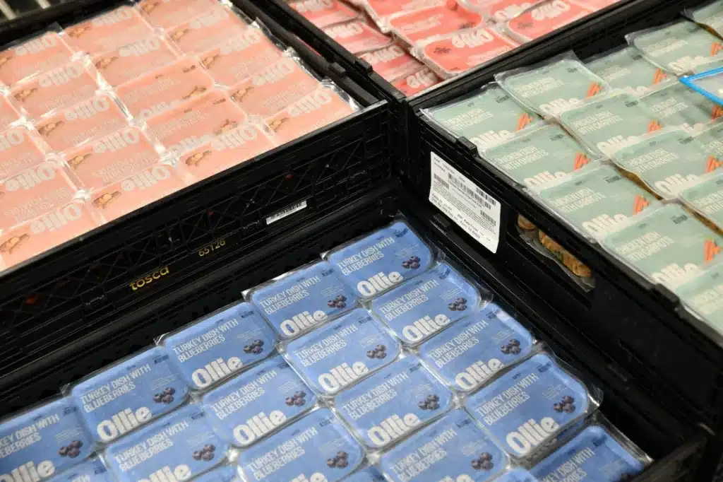 Ollie pet food treats in a Tosca reusable crate on a conveyor belt